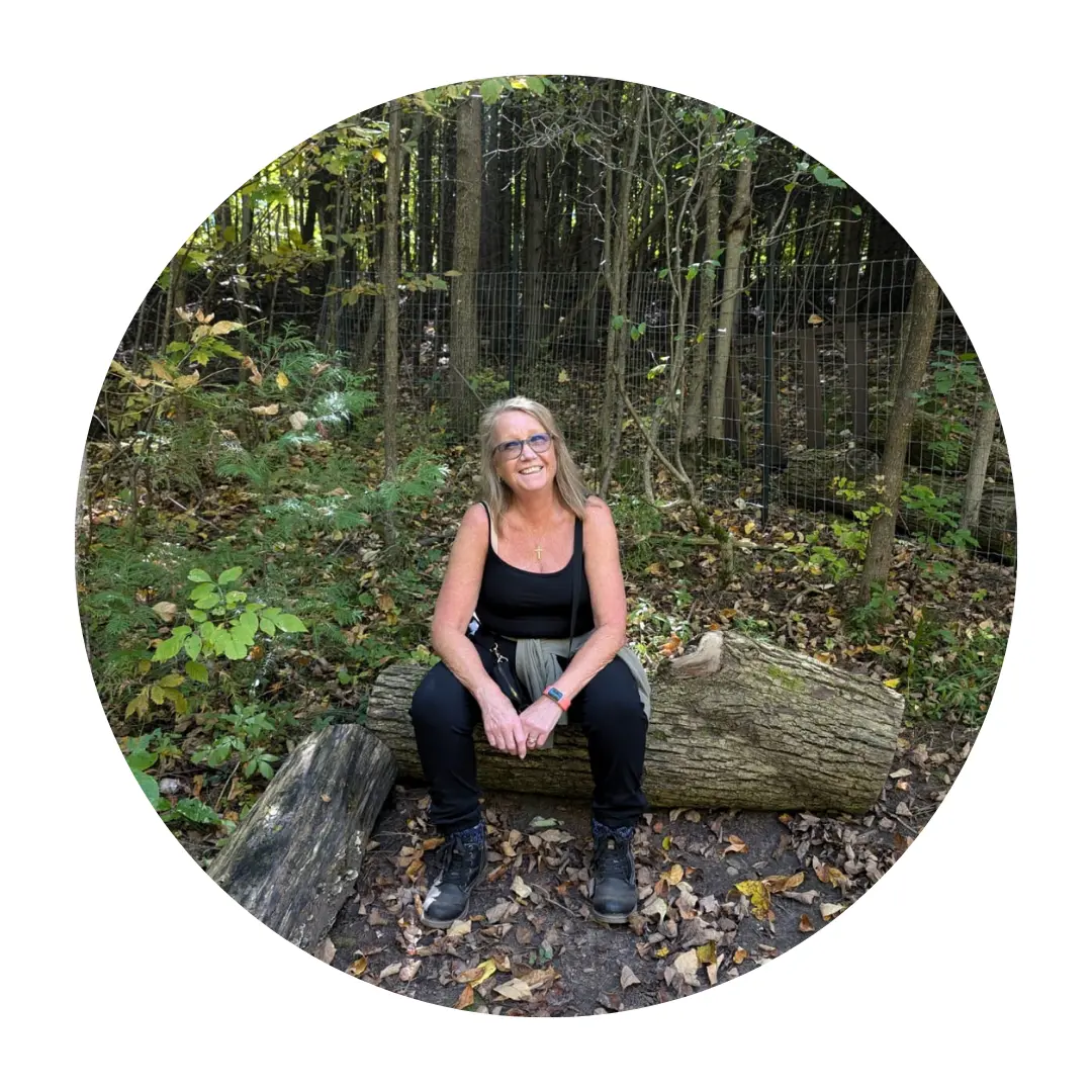 Pictured, Chris Plumb sat on a log in a forest