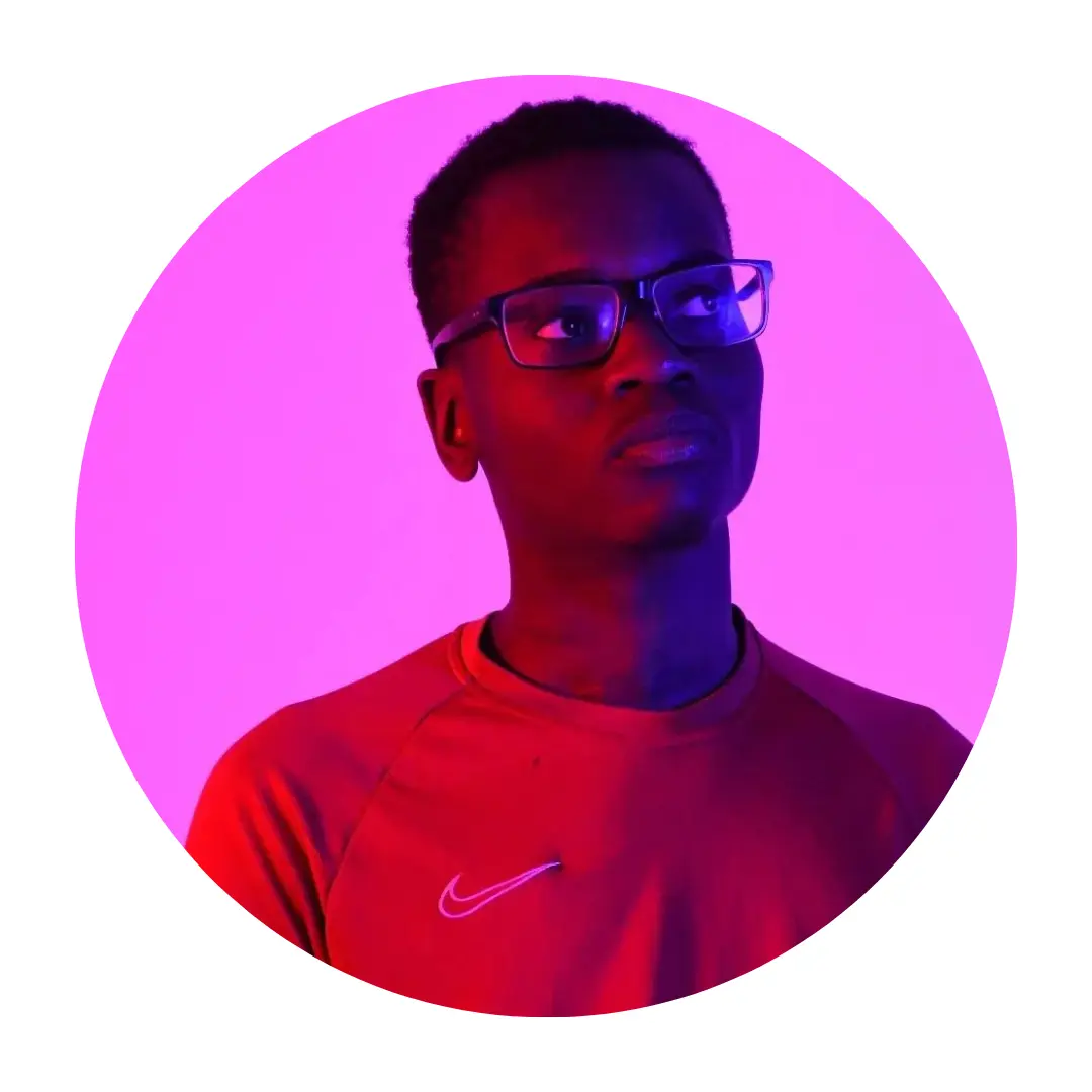 Pictured Daniel wearing glasses and a red Nike shirt, lit with purple and red lighting, looking slightly upward to the right