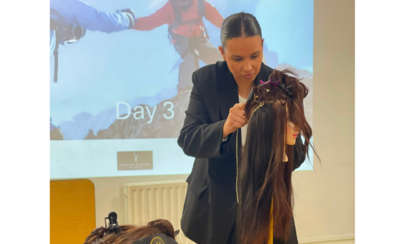 lady in black showing others how to put hair extensions in