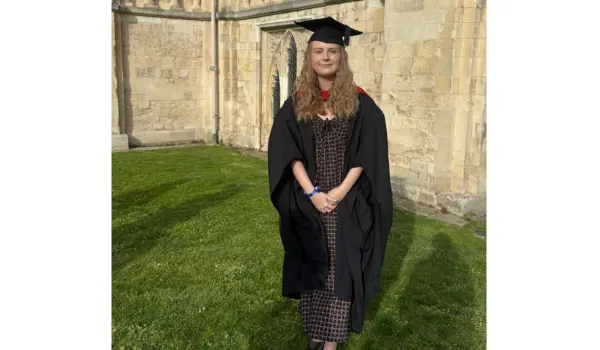 girl standing in black cloak and hat infront of a historic building