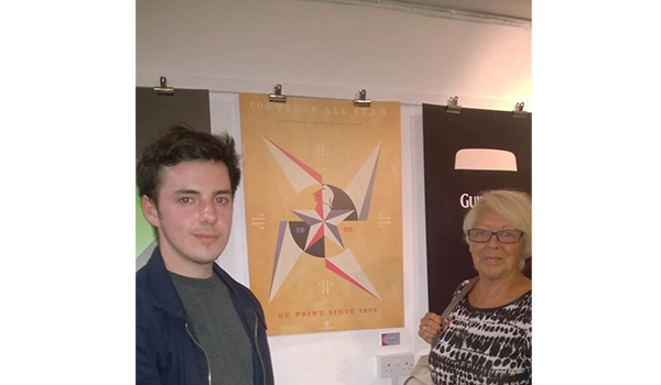 man with brown hair standing with lady with blonde hair infront of artwork