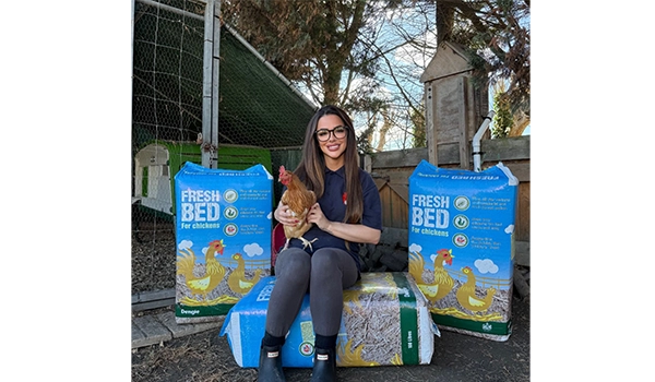 lady sitting on compost holding a chicken