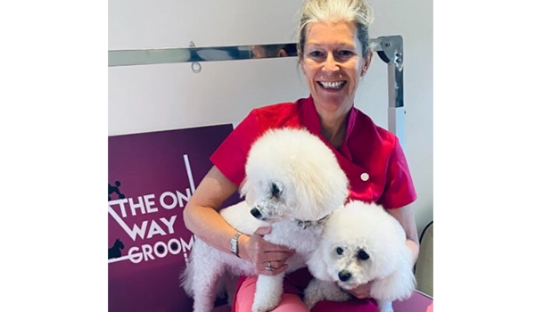 lady smiling holding two white dogs
