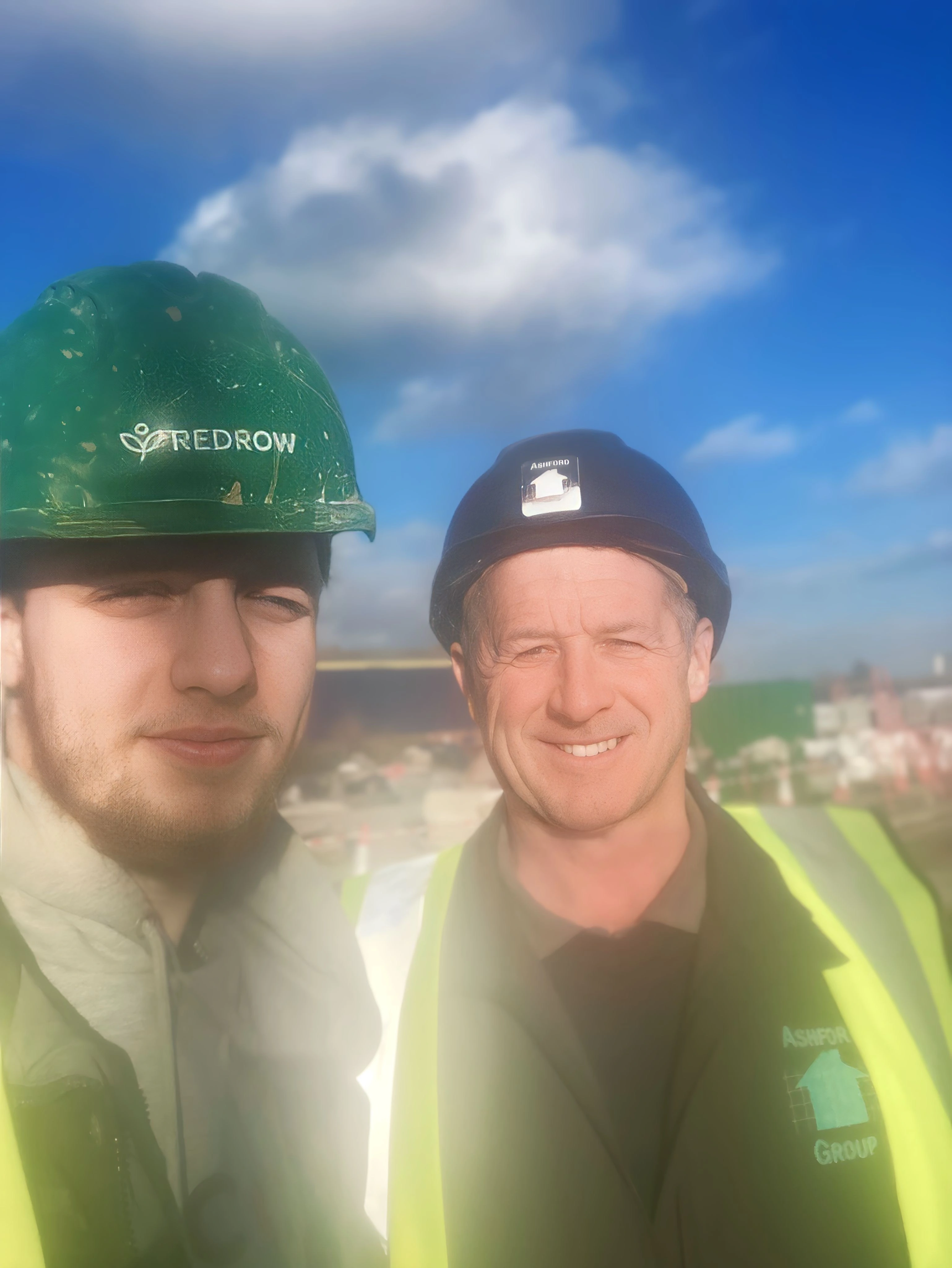 Two people wearing high vis and hard hats looking at the camera
