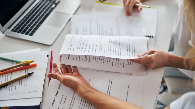 Student revising with notes and laptop