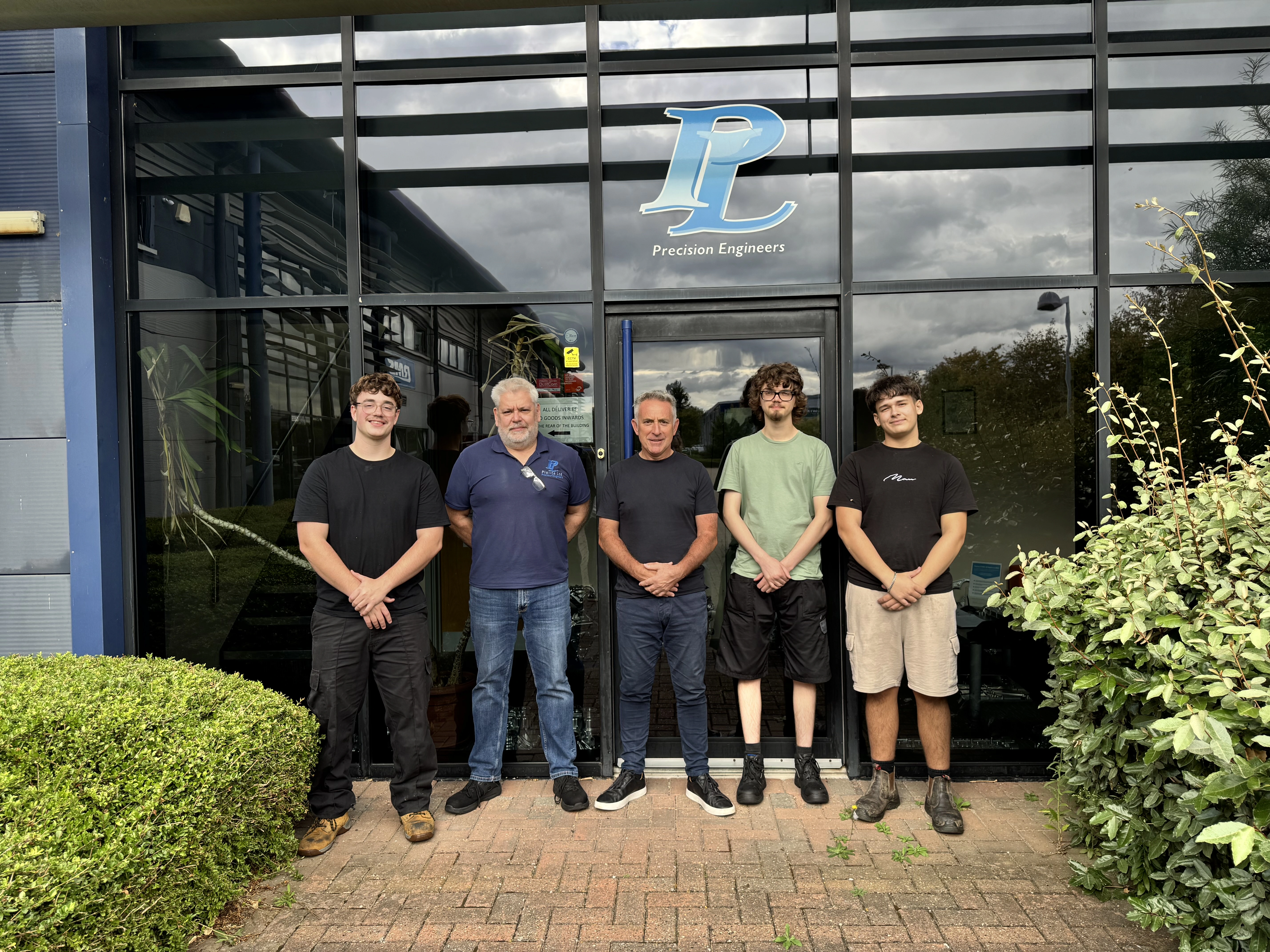 Three MidKent College students standing outside their new apprenticeship workplace with two of their managers