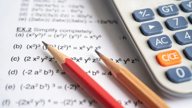 Image of maths work on a piece of paper with pencils and a calculator