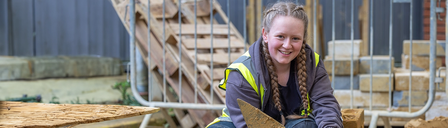 Construction student working in the bricklaying workshop looking at the camera and smiling