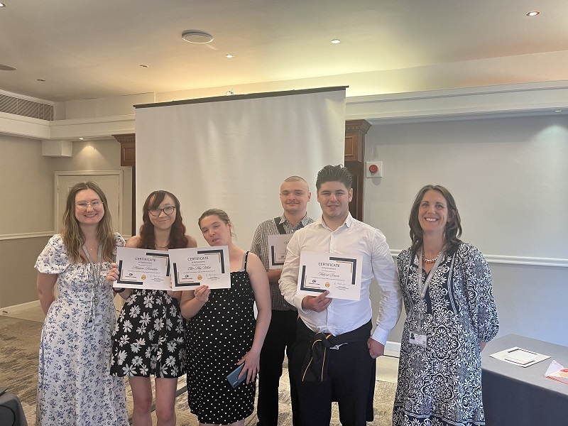 Group of interns holding their certificates looking at the camera
