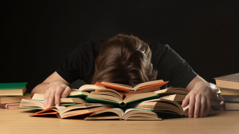 student looking stressed with head in books